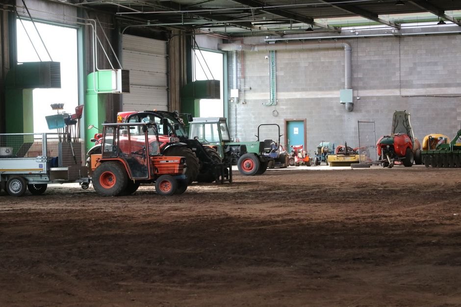 Image de divers tracteurs et machines agricoles stockés dans un grand espace intérieur
