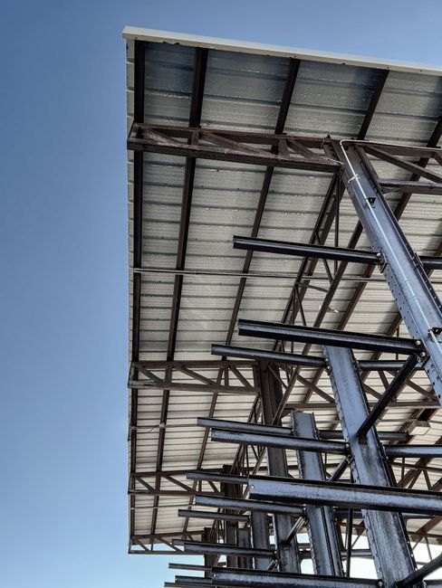 Une structure en acier industriel en construction sous un ciel bleu clair, mettant en valeur le design architectural